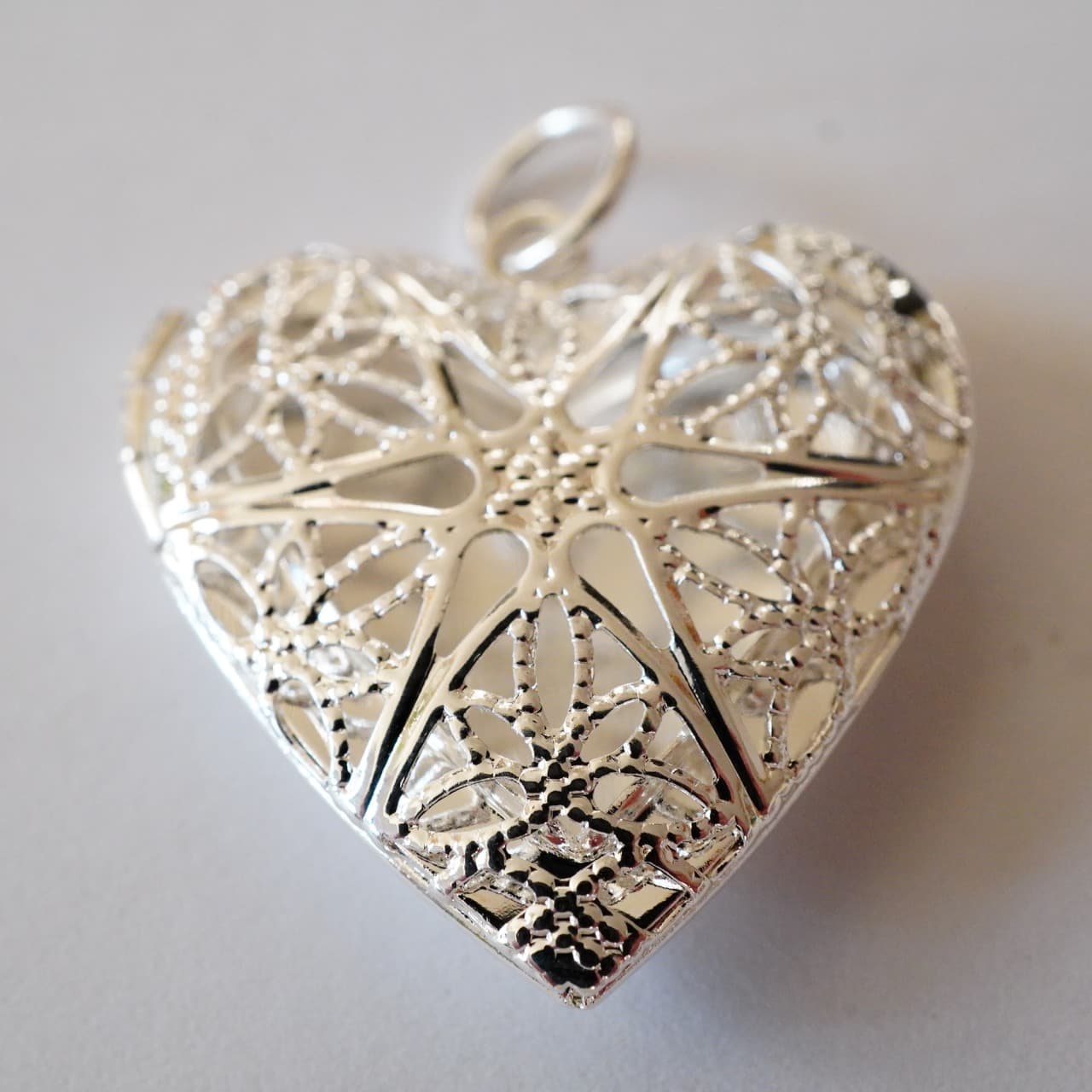 白い表面にハート型のシルバーフィリグリーペンダント。